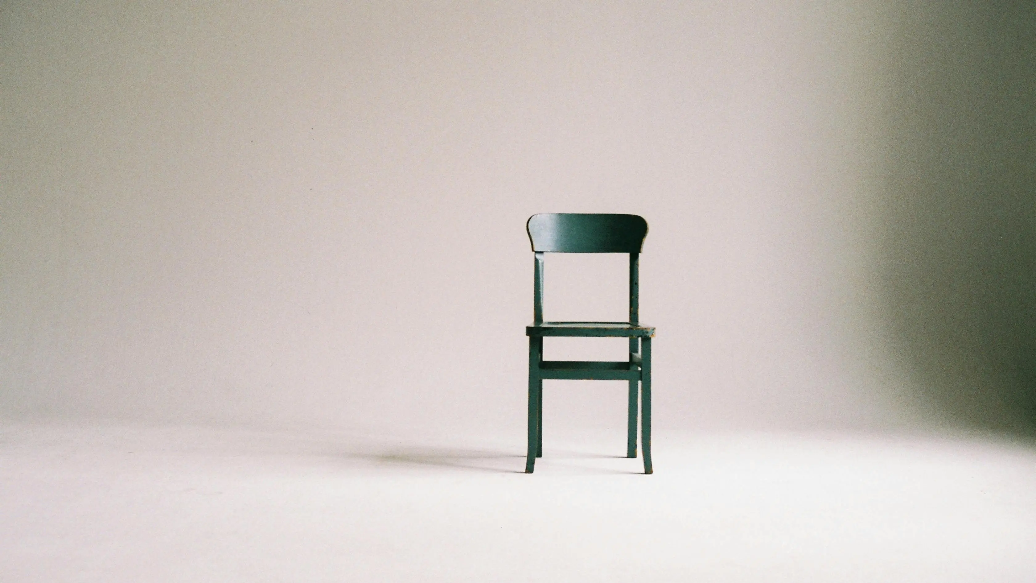 Wooden chair in a minimalist studio, evoking a poignant death scene ambiance