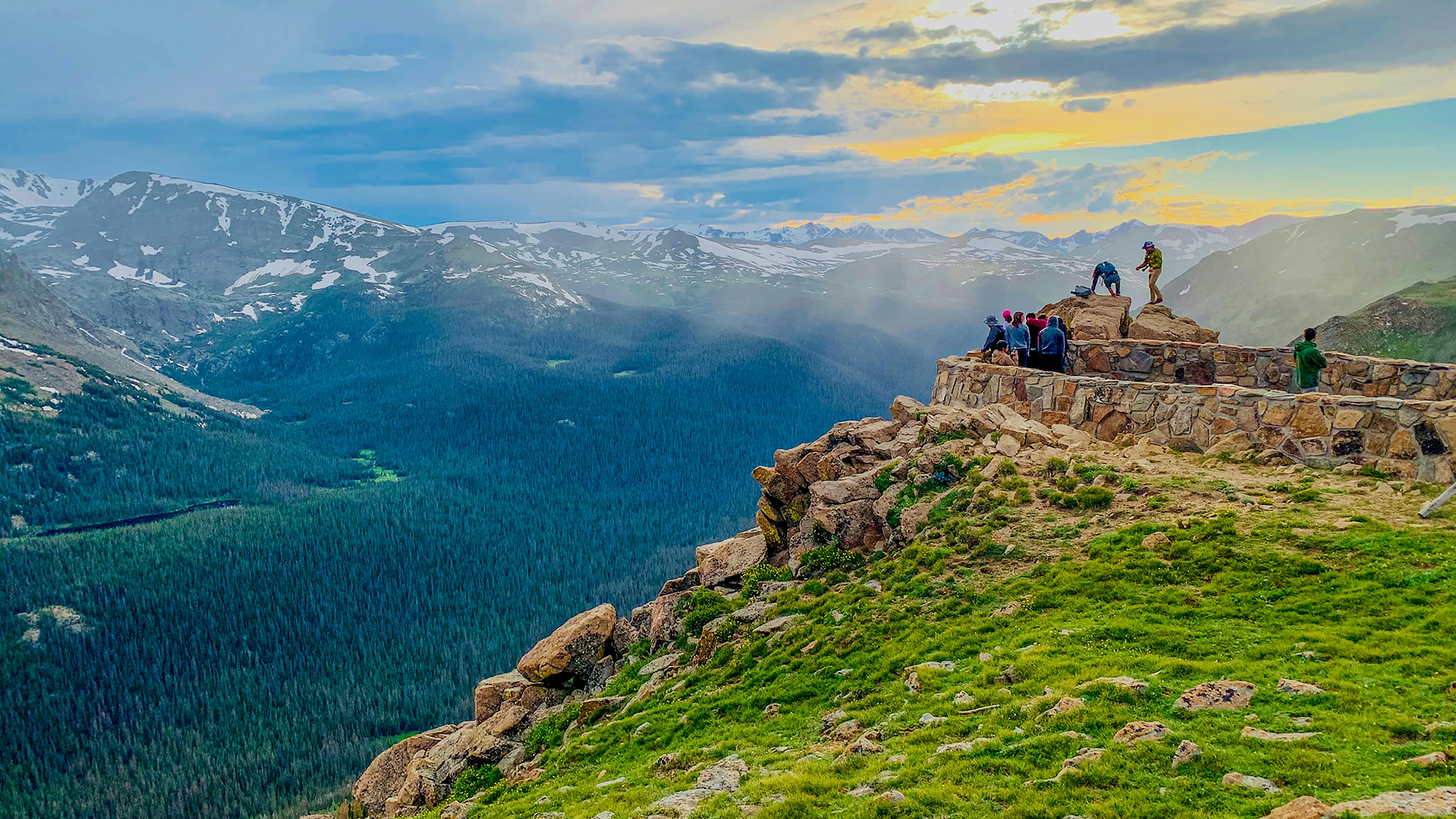 Travelers admiring sunset view at Rocky Mountain National Park, symbolizing protagonist goal of adventure