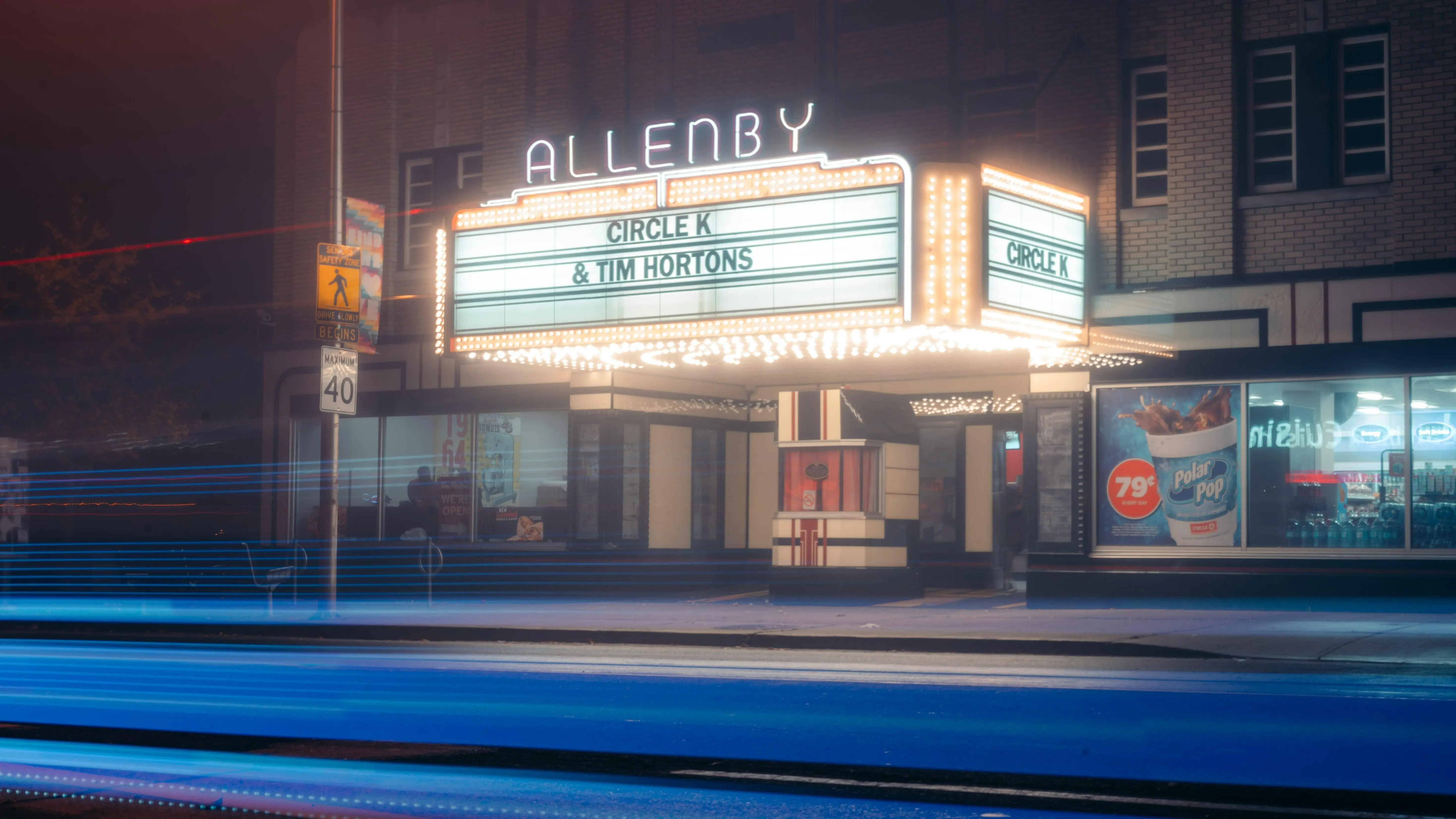 Neon-lit cinema on city street at night, symbolizing screenwriters' employment in Hollywood.