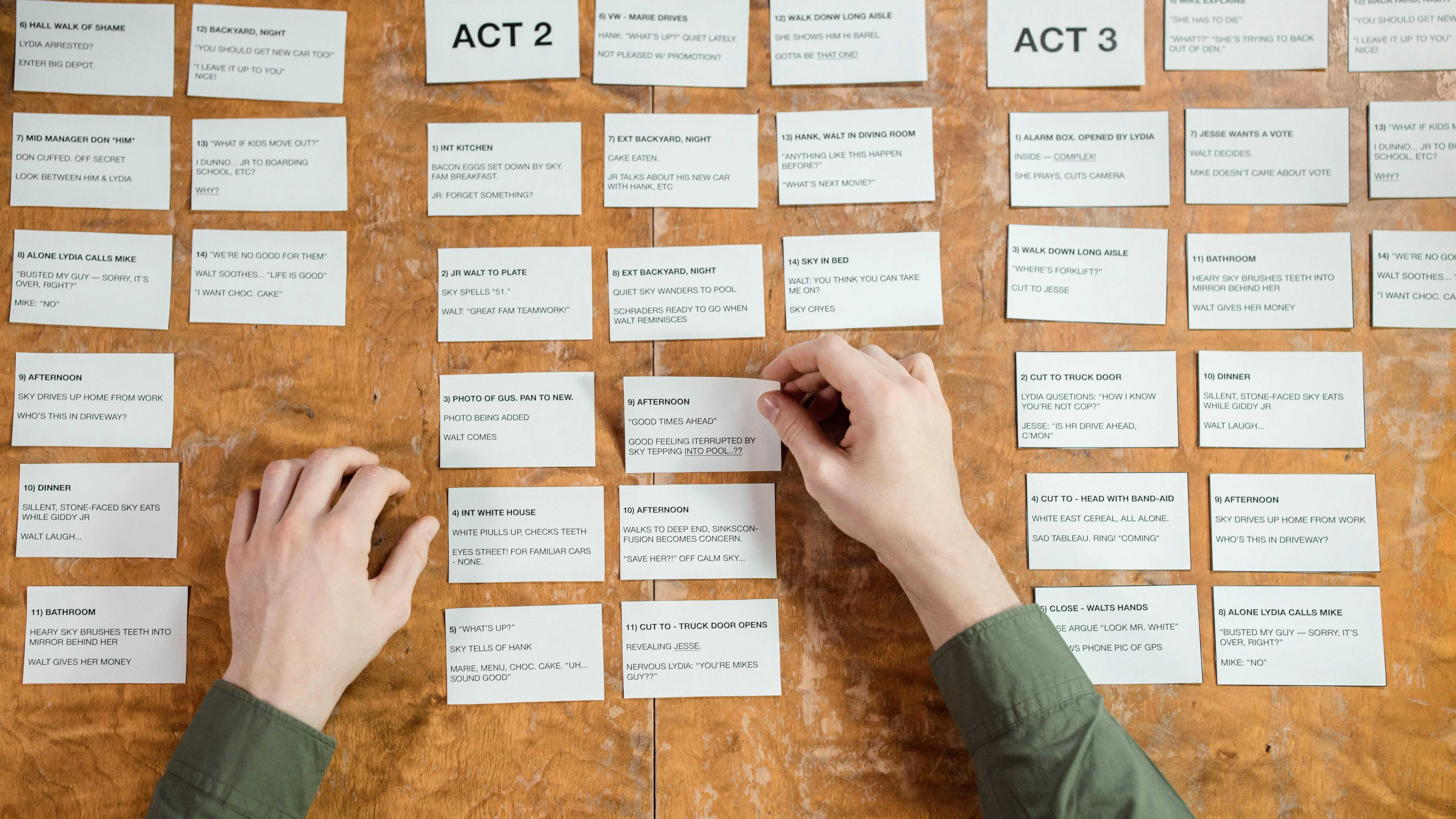 Man organizing cards with play acts on table for screenwriting coverage tips