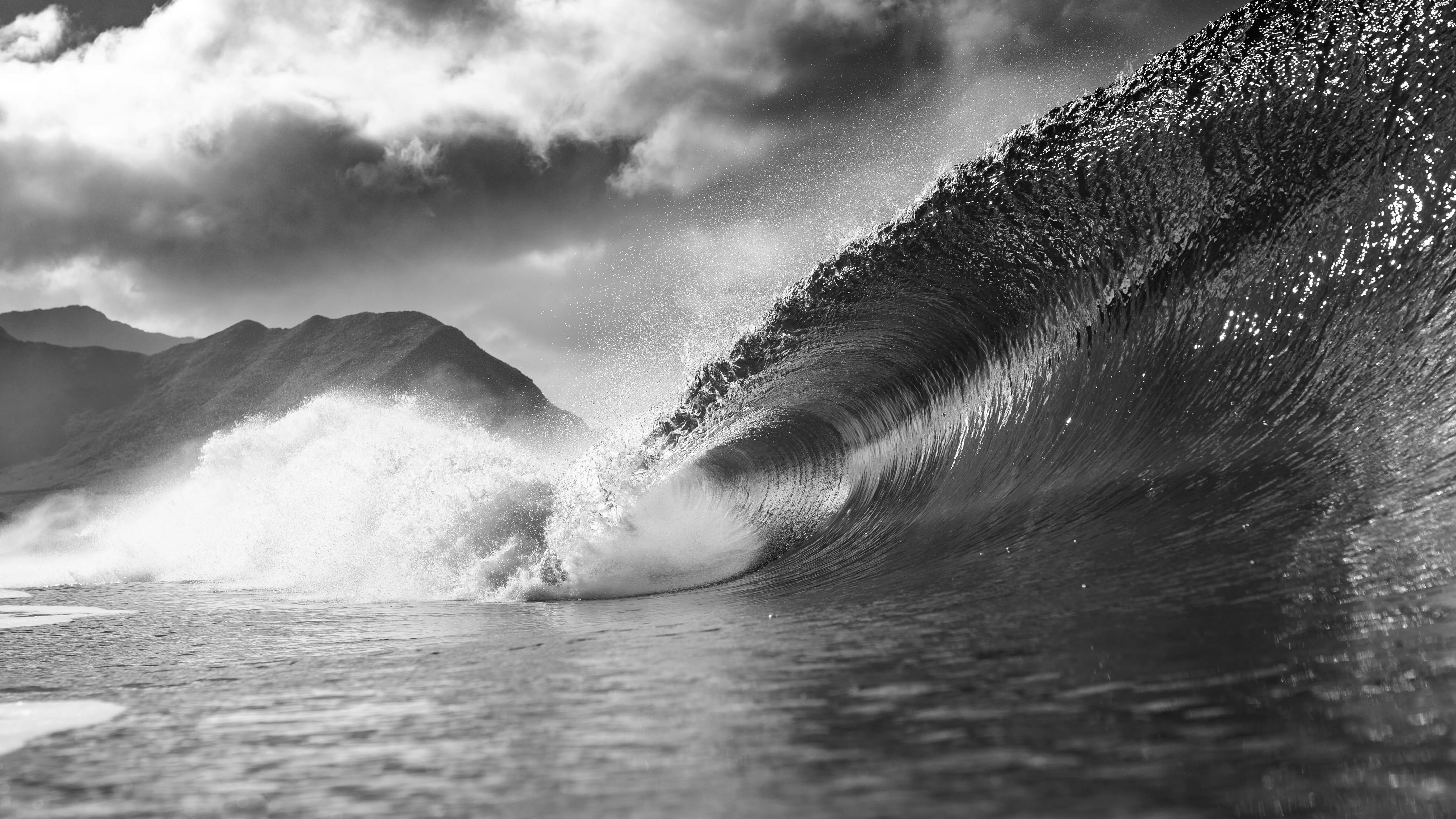 Foamy wave splashing into the ocean beneath a cloudy summer sky