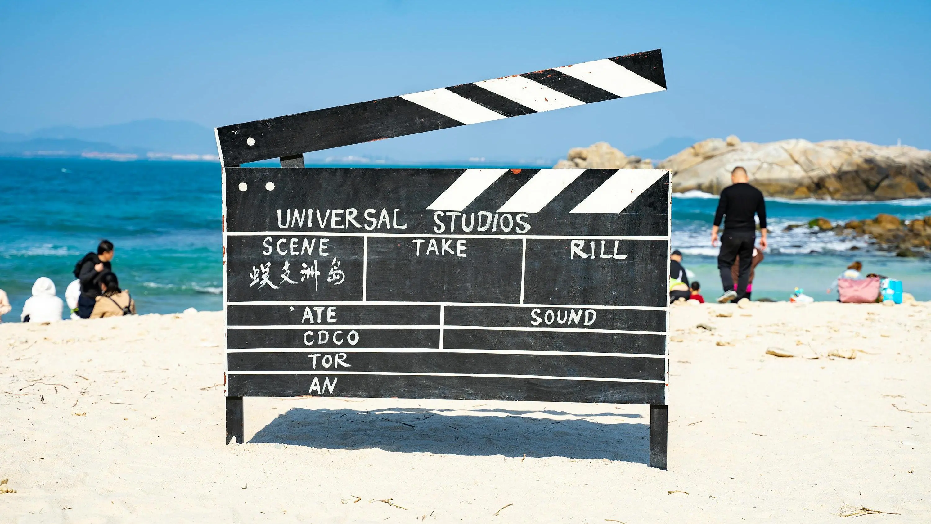 Clapperboard on sandy beach promoting short screenplay contest