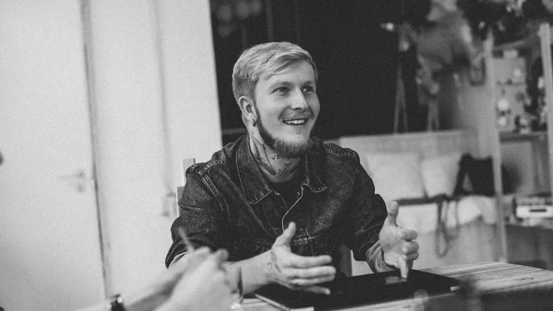 Male hipster discussing tips for comedy pitch with colleague in workspace