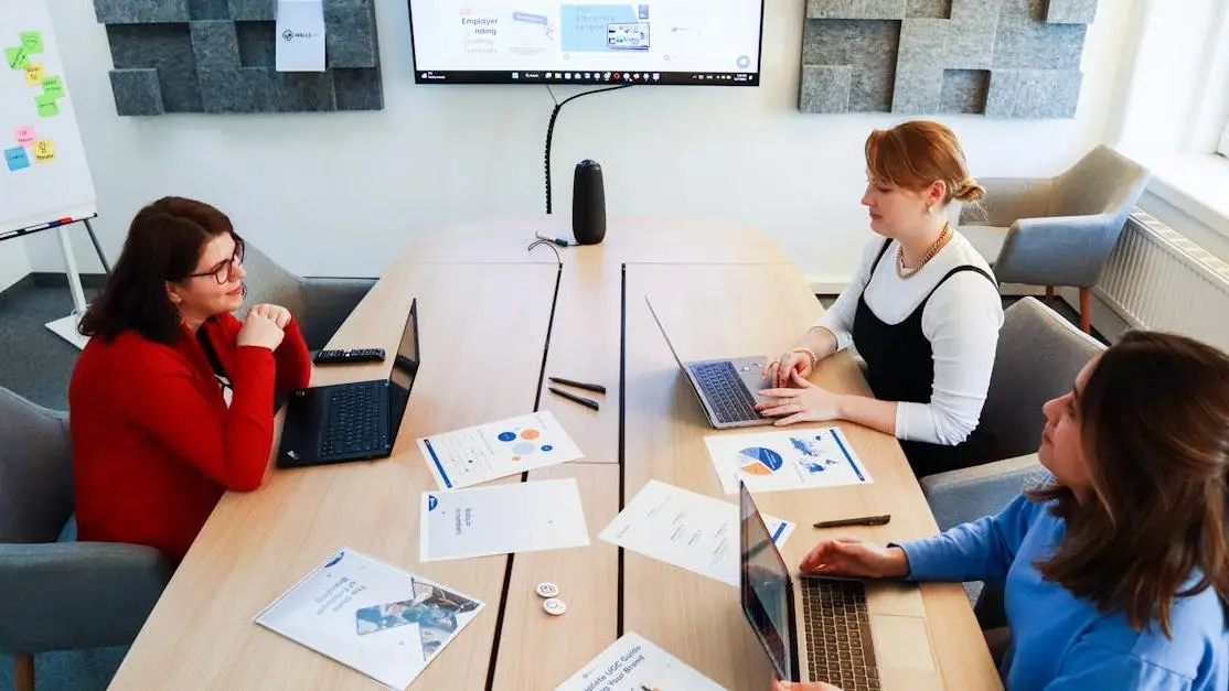 Women discussing TV writers' room hierarchy in a meeting setting