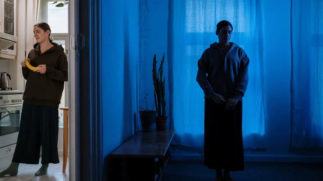 Woman in shadowy room with opposing backdrops, representing writing complex characters and inner conflict