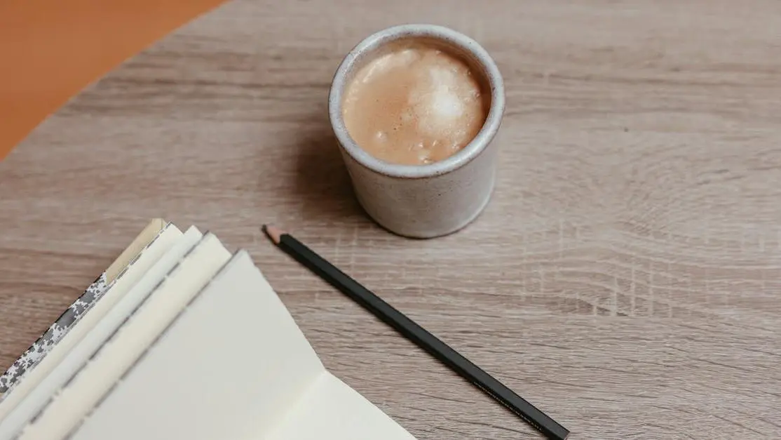 Cozy workspace with coffee, open notebook, and pencil for writing a strong synopsis