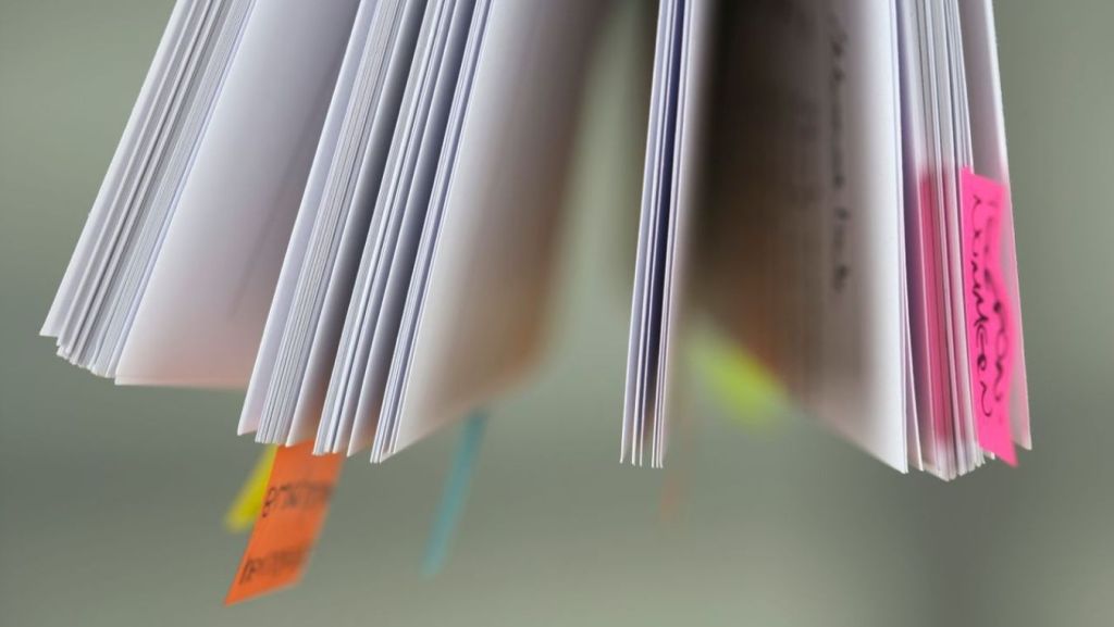 Close-up of a printed TV pilot script organized with colorful sticky tabs for script coverage, notes, and showrunner development workflows