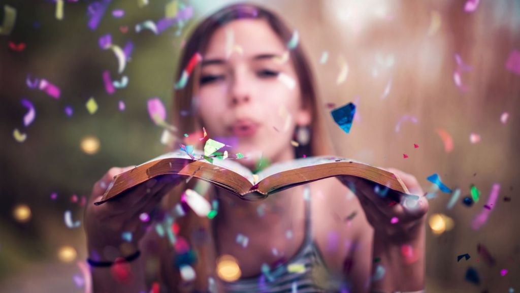 Woman blowing colorful confetti off an open book, symbolizing how script coverage readers uncover subtext and layered subplots.