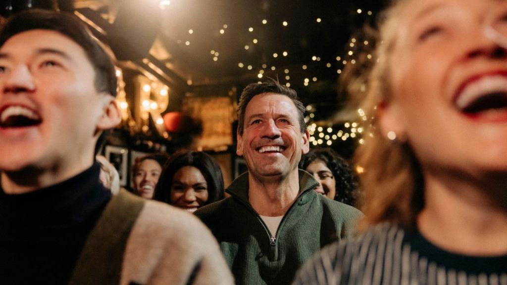Diverse audience laughing at a comedy show, illustrating how AI script coverage readers evaluate comedy screenplays.