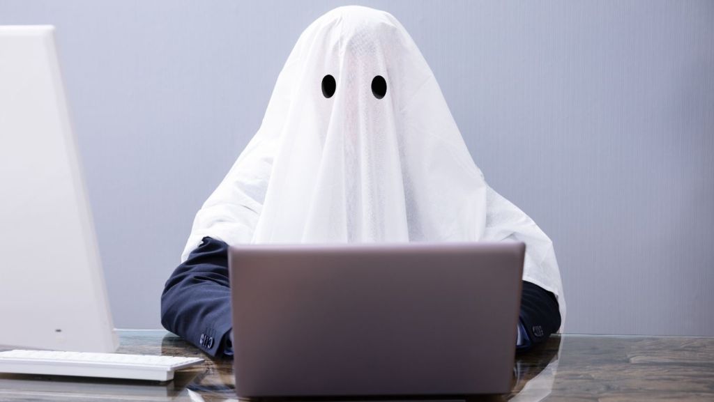 Person wearing a ghost costume sitting at a laptop computer, illustrating AI short film script coverage and sub-30-page formats.